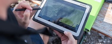 Ein junger Mensch trägt am Tablet Daten in eine topografische Karte ein
