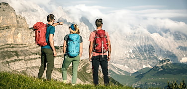 Drei Wandernde vor Bergkulisse