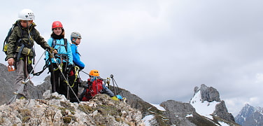 drei Jugendliche auf einem Klettersteig. 