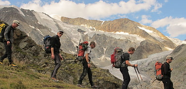 group of hikers descending on a trail in front of a mountainrange 