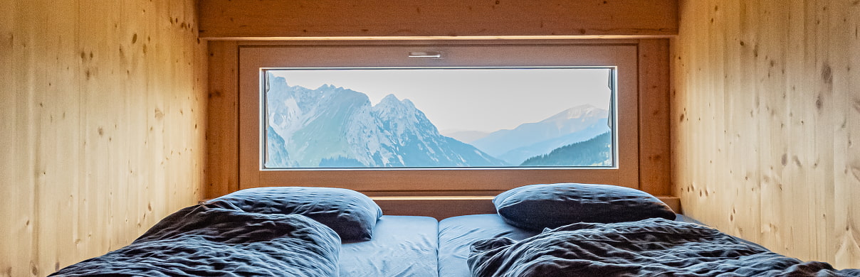 zwei Betten mit großem Fenster und Ausblick auf die Lalidererwände 