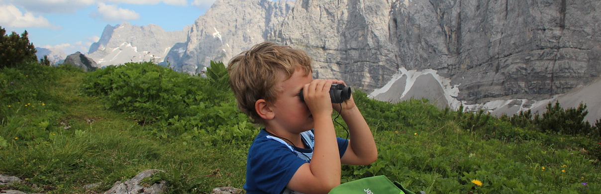 Kind mit Fernglas vor Bergkette 