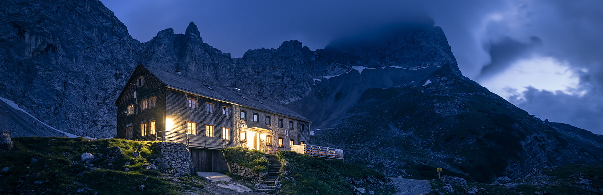 Blick auf beleuchtete Lamsenjochhütte bei Nacht vor Bergpanorama
