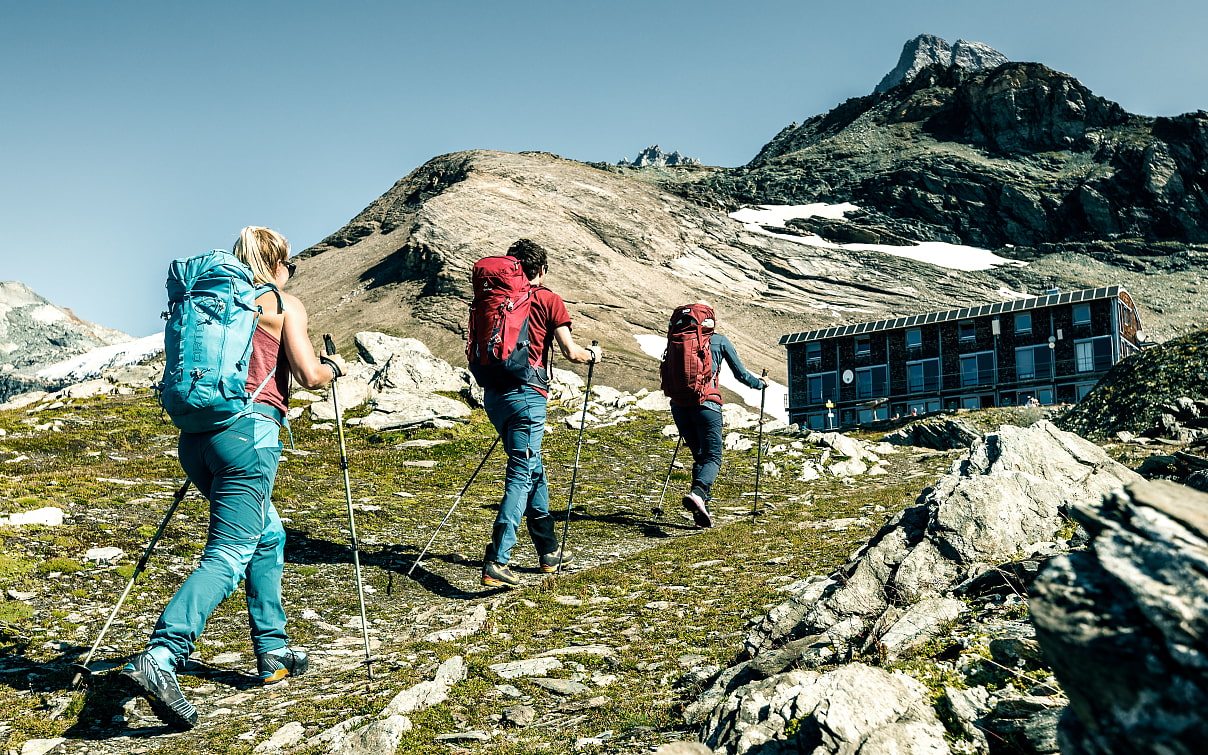Drei Wandernde auf dem Weg zur Hütte 