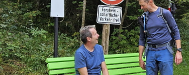 DAV-Mitfahrbankerl mit zwei Personen und Auto