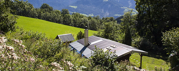 Bild zeigt die Hütte kleine Aste-Reitbichl Hütte von oben gelegen an einer grünen Berghangwiese