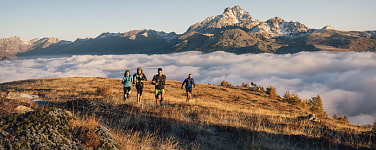 Trailrunner laufen über Nebelmeer im Tal den Berg hinauf