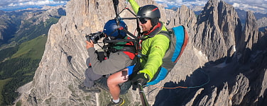 Zwei Männer in einem Paraglider hoch über felsigen Bergen