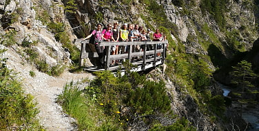 Die Tourteilnehmer stehen als Gruppe auf einer Holzbrücke vor einem Steilhang.