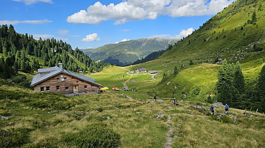 In einer saftig grünen Berglandschaft steht links im Bild die Neue Bamberger Hütte.