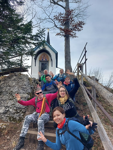 Eine Gruppe vor der Riedersteinkapelle. Alle strecken ihre Hände in die Luft.