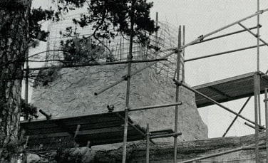 Schwarz-Weiß Aufnahme zeigt den Bau des Kletterbrockens, der von einem Gerüst umstellt ist