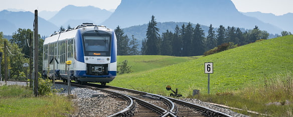 Bild zeigt den BOB Abkürzung für Bayerische Oberland Bahn von vorne wie er zu einer Gleiszweigung kommt im Voralpenland 
