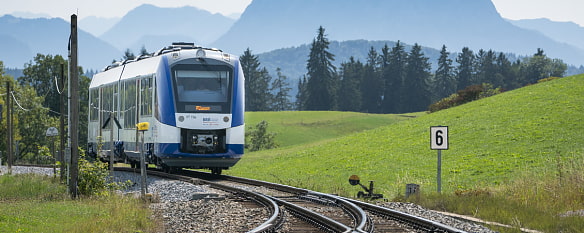 Bild zeigt den BOB Abkürzung für Bayerische Oberland Bahn von vorne wie er zu einer Gleiszweigung kommt im Voralpenland 