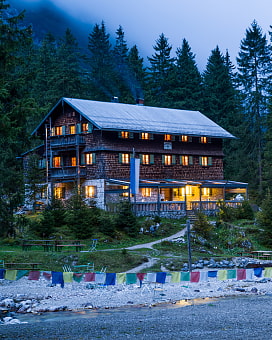 Reintalangerhütte beleuchtet bei Nacht. Im Vordergrund ist das Flussbett der Partnach.