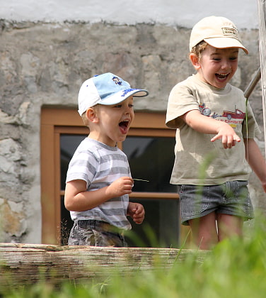Spielende Kinder an einem Brunnen vor der Hütte