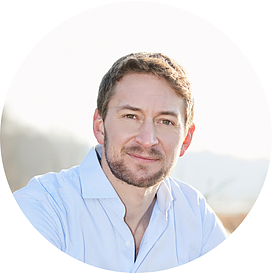 Das Bild zeigt ein rundes Portrait von Dr. Matthias Ballweg, Vorsitzender. Er hat kurz geschnittene, hellbraune bis dunkelblonde Haare und einen kurz geschnittenen Vollbart. Er trägt ein hellblaues Hemd mit 2 geöffneten Knöpfen am Kragen. Der Hintergrund ist unscharf und es wirkt als befinde er sich im Freien. Es ist eine sehr helle Landschaft im Hintergrund.