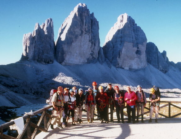 Die Ortsgruppe Eching-Neufahrn auf der Dreizinnen-Hütte, 13 Teilnehmerinnen und Teilnehmer in voller Bergsteigerausrüstung. Im Hintergrund die drei Zinnen der Dolomiten.