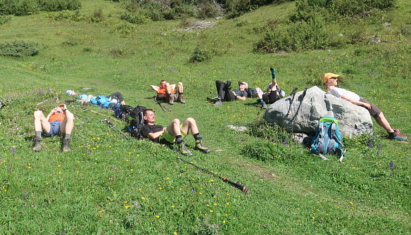 Nach der Dreitagestour auf die Parseierspitze liegen die Teilnehmerinnen und Teilnehmer in der Sonne auf der Wiese.