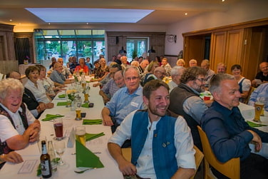 Das Bild zeigt einen gut besuchten Gruppenabend im Gasthaus. Im Vordergrund der Vorsitzende der Sektion Oberland Matze Ballweg, der Geschäftsführer Andi Mohr und der Neufahrner Bürgermeister Franz Heilmeier, der auch Alpenvereinsmitglied ist.