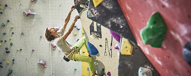 Ein Kletterer an der Kletterwand in einer Kletterhalle