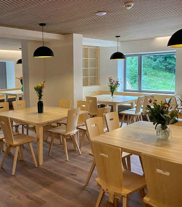 Helle, moderne Gaststube mit Holztischen und Stühlen