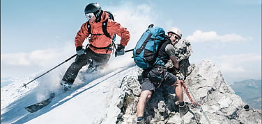 Geteiltes Bild: Im Vordergrund Sommerlandschaft mit Wanderndem am Berg. Im Hintergrund Skifahrer an verschneitem Berghang