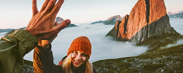 Ein Bergsteiger schlägt mit einer Bergsteigerin ein, im Hintergrund sind Berge zu sehen.