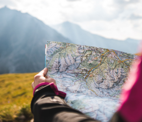 Eine Person in den Bergen die eine Topografische Karte in der Hand halt