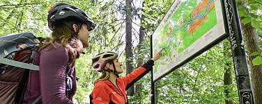 Zwei Mountainbikerinnen vor einem Geländeplan im Isartal