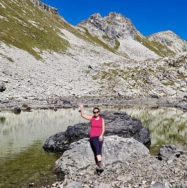 Jennifer Bode vor einem Bergsee mit Bergen im Hintergrund.