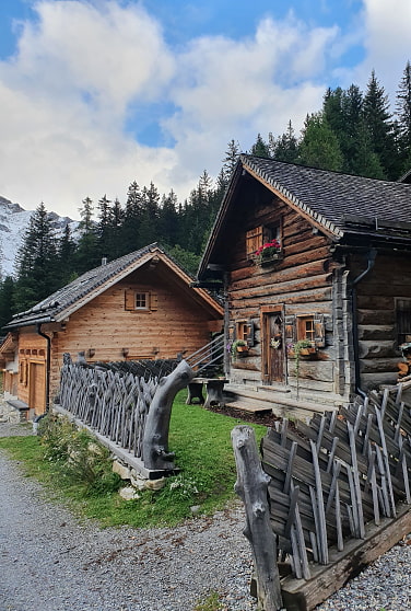 Zwei Blockhaushütten aus Holz mit Jägerzaun in den Bergen