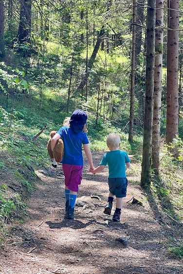 Zwei Kinder wandern Hand in Hand durch den Wald