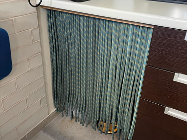 Vorhang aus altem Seil vor den Mülleimer unter der Arbeitsfläche in einer Küche