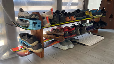 Quer sind Ski an zwei Holzstützen befestigt, auf den Ski stehen Schuh.