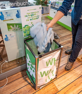 Mann wirft eine Jacke in einen Why-waser-it?-Sammelständer