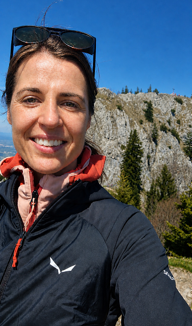Martina mit Jacke vor einem felsigen Berg.