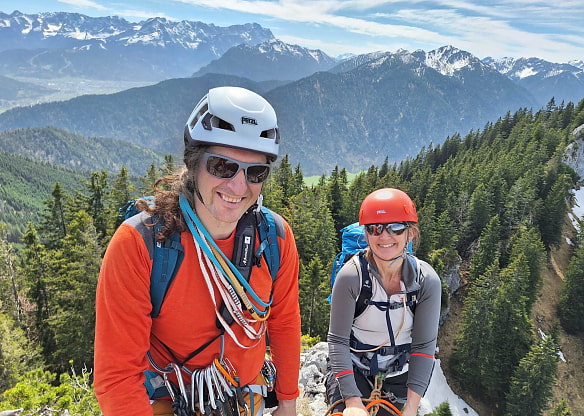 Mann und Frau mit Kletterequipment vor Bergpanorama