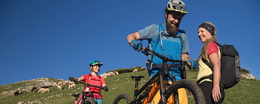 Zwei MTB-Fahrer schieben ihr Rad vorbei ein an einer lächelnden Wanderin.