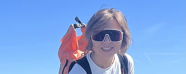 Frau mit Sonnenbrille und orangenem Rucksack