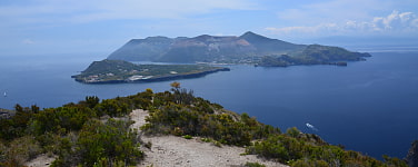 Blick von einem Berg hinab auf das Meer und bergige Inseln