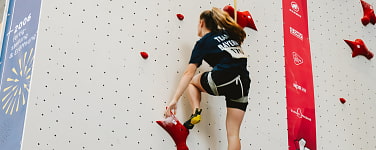 Junge Frau klettert an einer Speed-Kletterwand